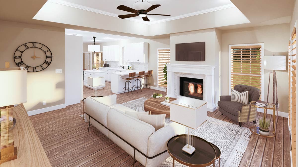Interior view of open concept living area with fireplace, kitchen island with bar stools, and white cabinetry.