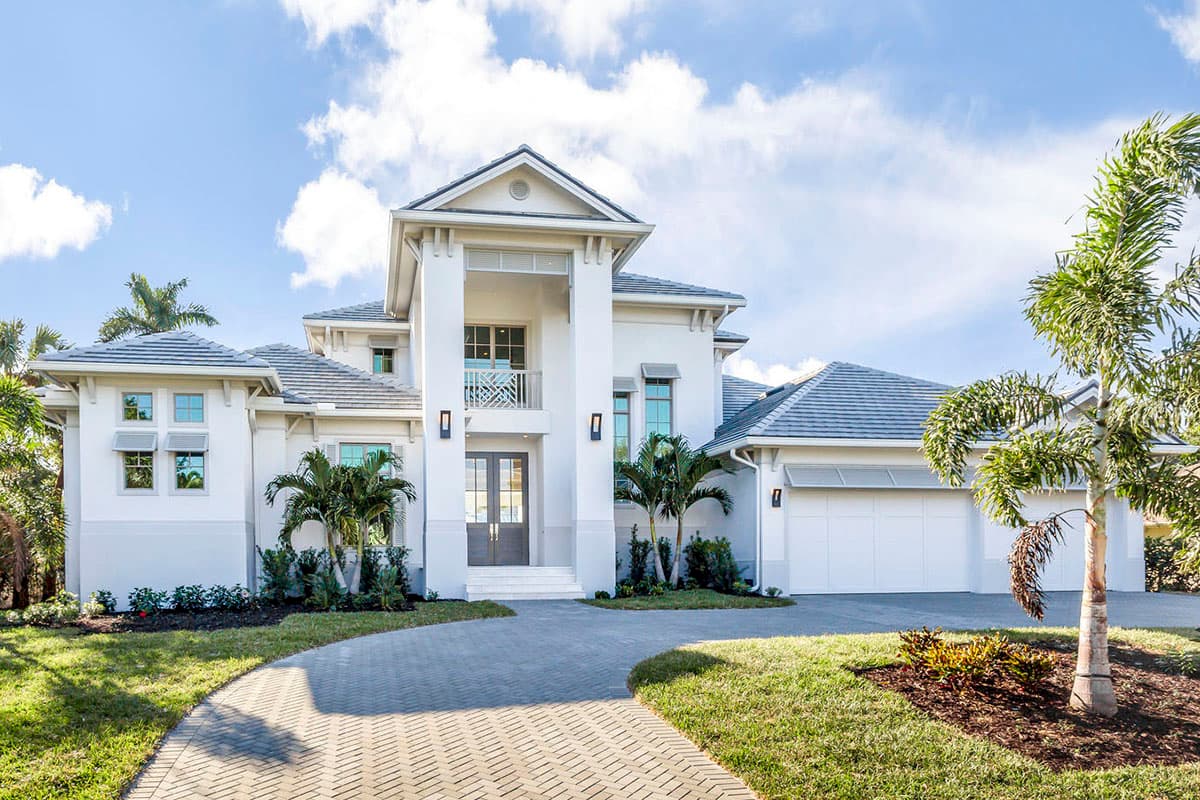 House plan exterior. Two-story home with a portico entry, balcony, and attached garage. Features include a hipped roof and paired columns.