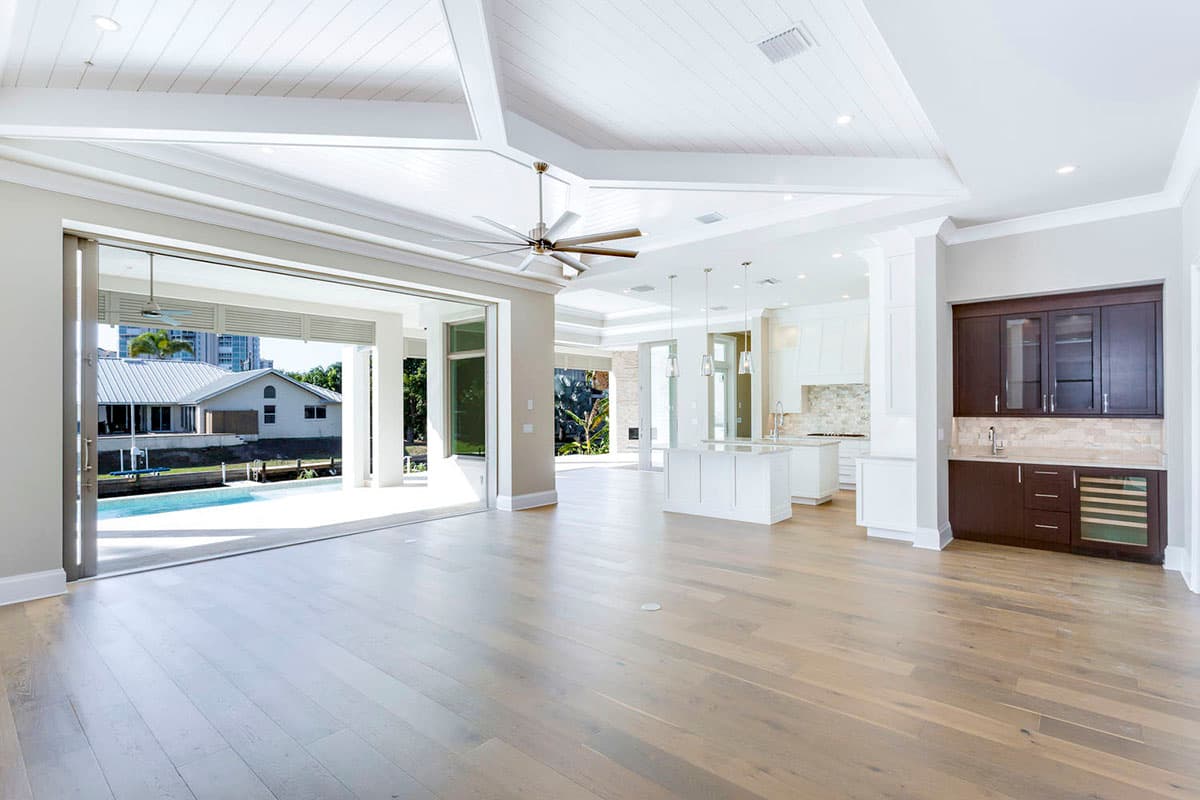 Open-concept living space with vaulted plank ceiling, large sliding glass doors, kitchen island, and wet bar.