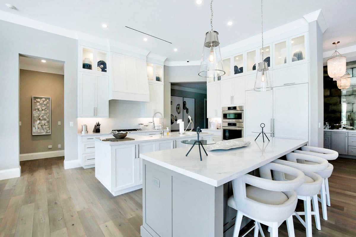 Modern kitchen with large island, white cabinetry, stainless steel appliances, and pendant lighting.