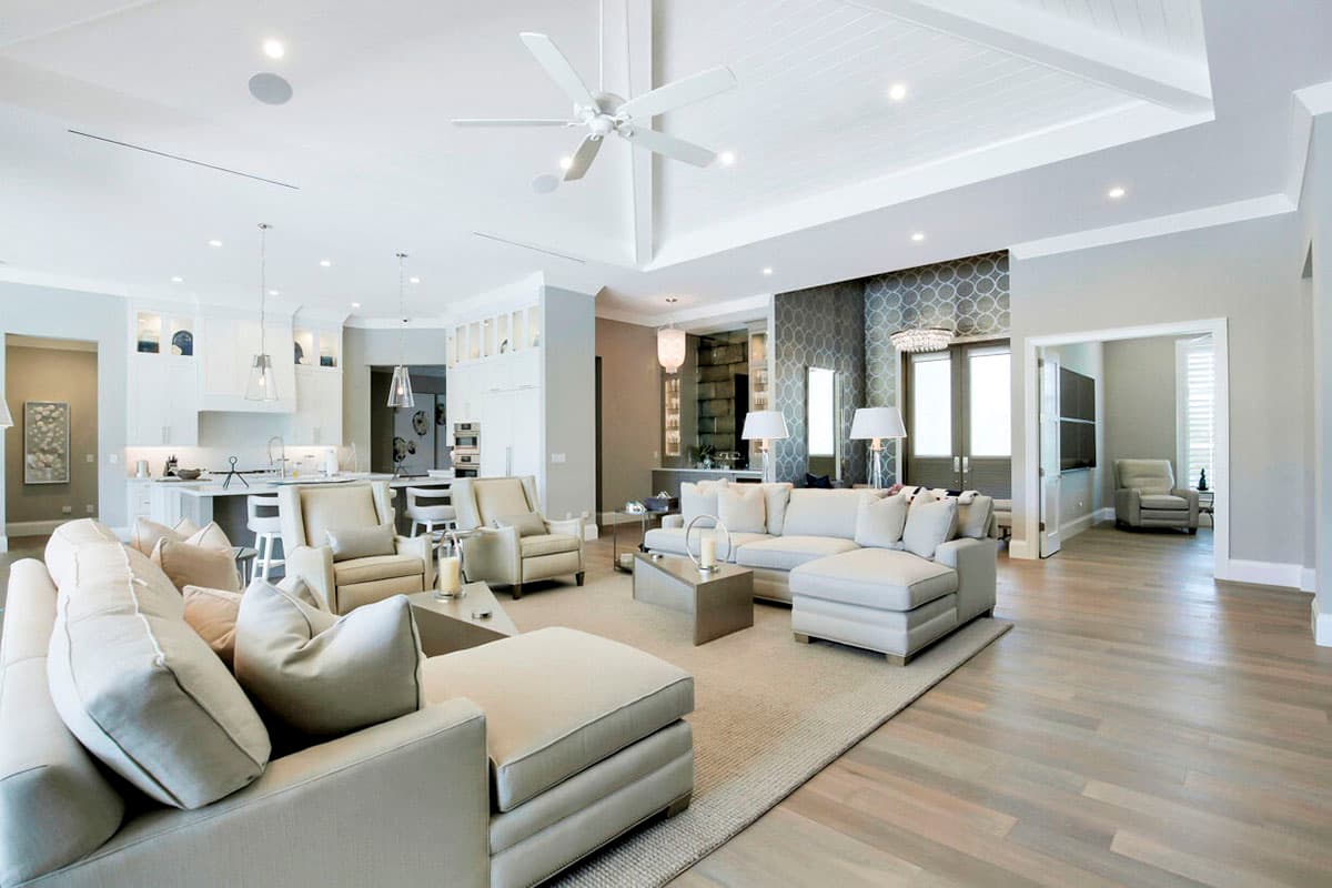 Open-concept living area with a coffered ceiling, recessed lighting, ceiling fan, and connecting kitchen.