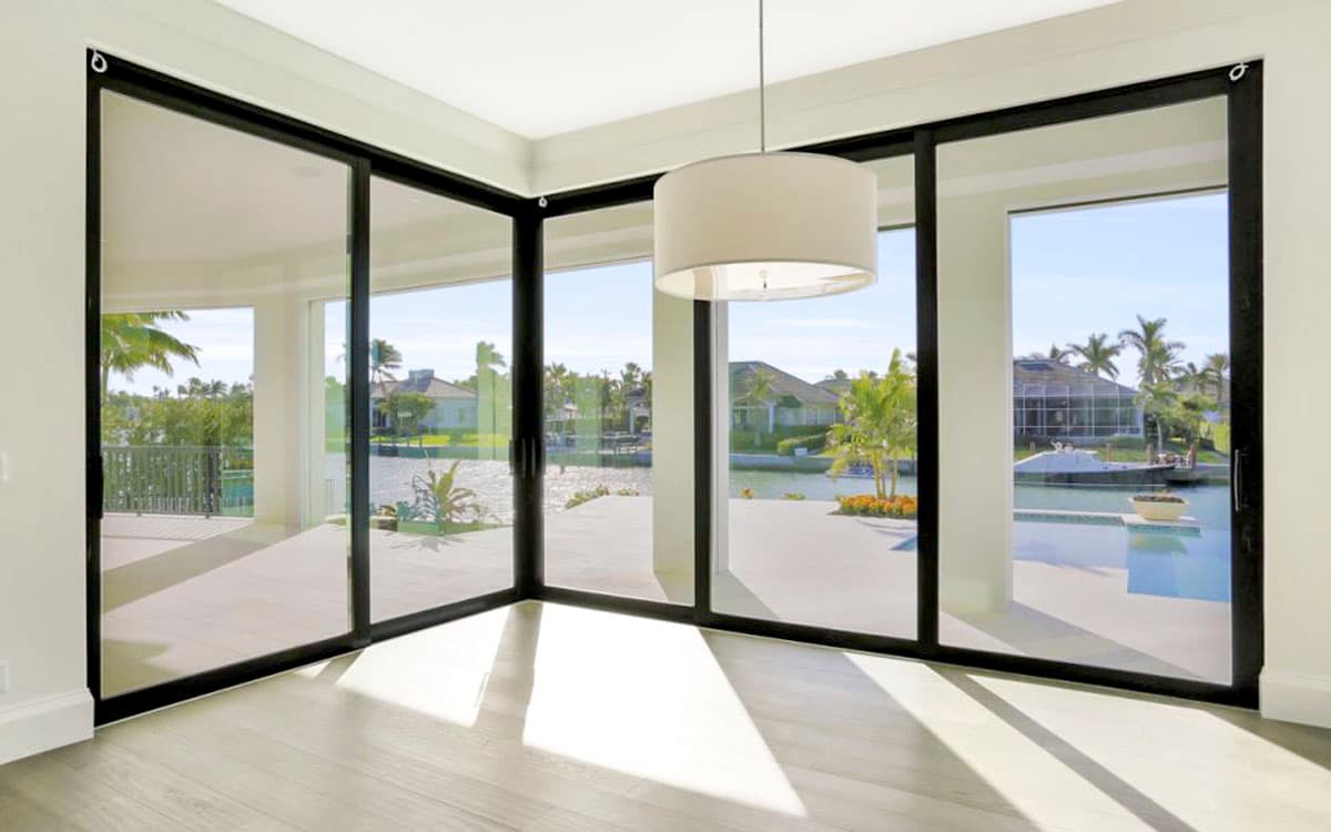Interior view of a room with large corner sliding glass doors opening to a patio and water view.