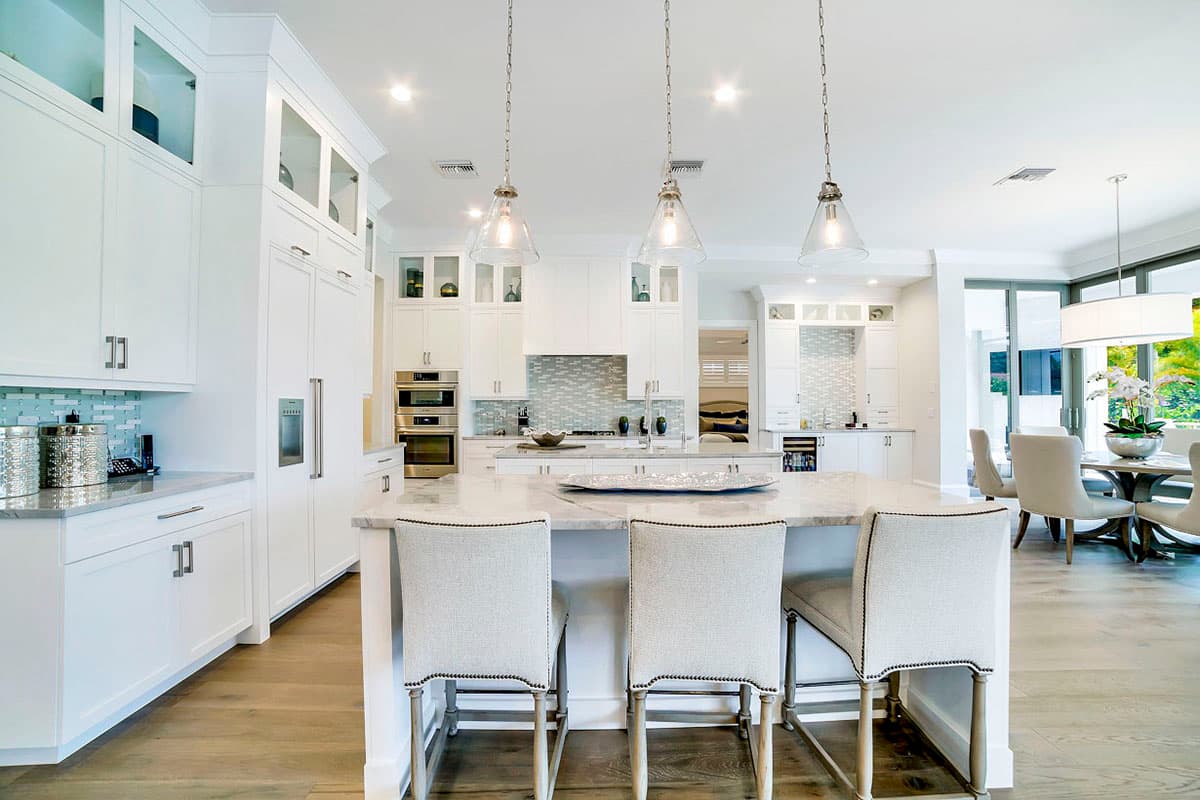 Open-concept kitchen with a large island, white cabinetry, dual ovens, and pendant lighting.