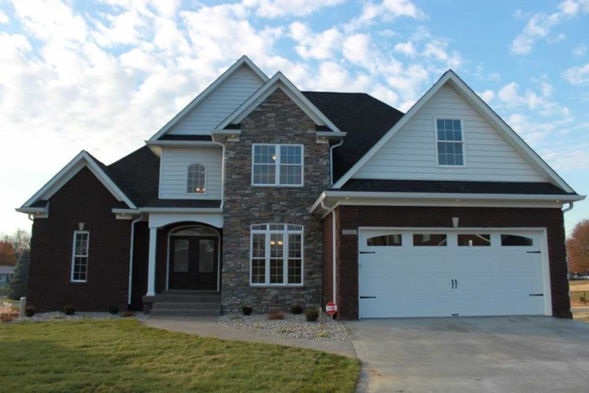 Two-story house plan exterior with brick and stone facade, arched entryway, and attached garage.