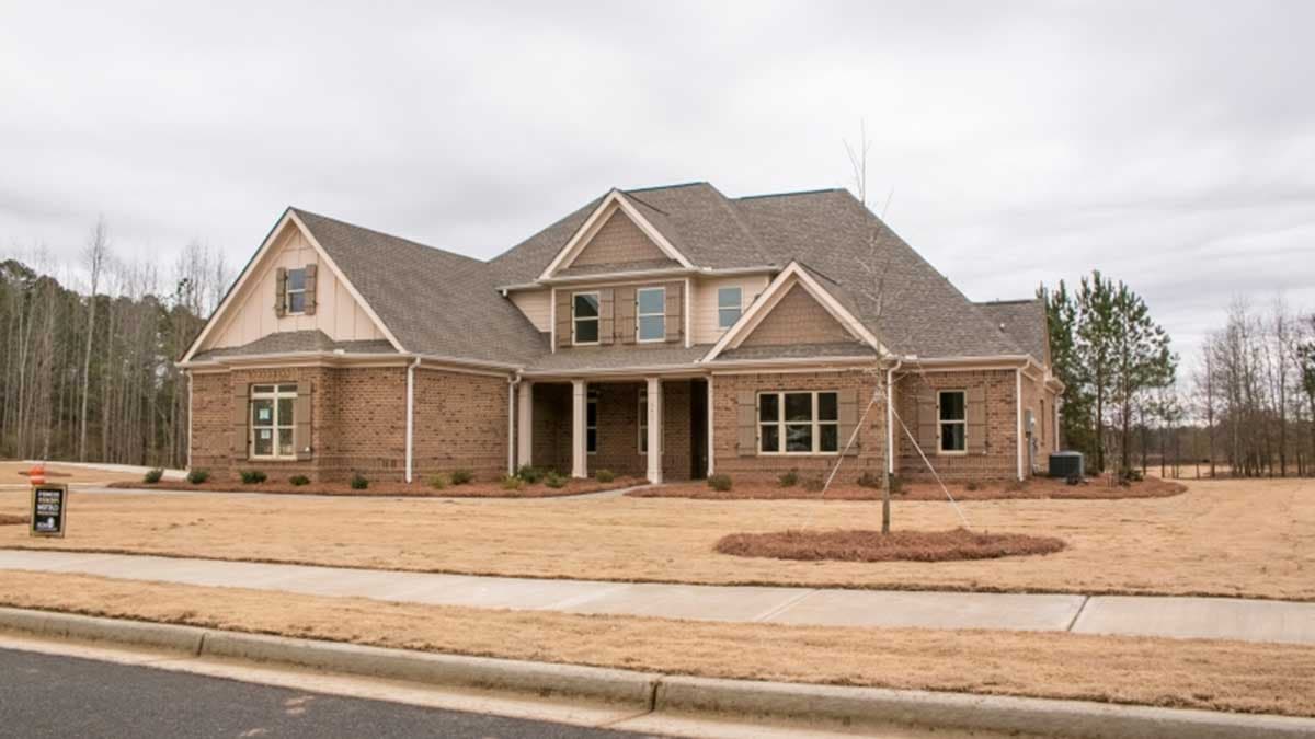 House plan exterior. Two-story brick home with a gable roof, covered porch, and dormers. Features include shutters and multiple windows.