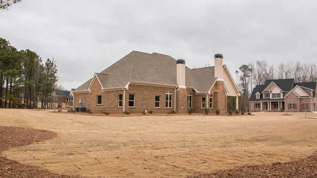 One-story brick house plan exterior with gabled dormers, prominent chimneys, and a covered entryway.