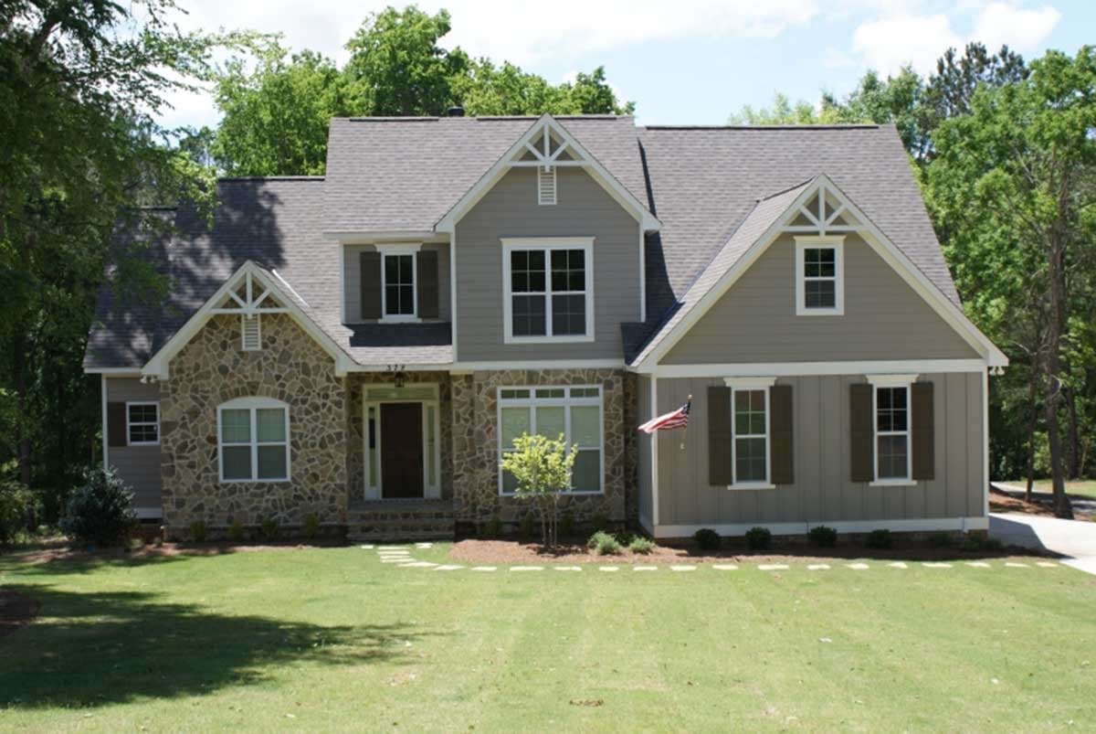 House plan exterior. Two-story home with Craftsman style. Features include stone veneer, gabled rooflines, decorative gable trim, and shutters.