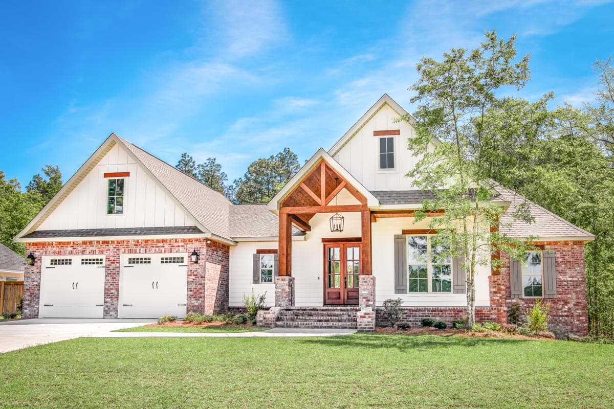 Modern Farmhouse exterior with a side-entry three-car garage, brick accents, and a wood-beam covered entry porch.