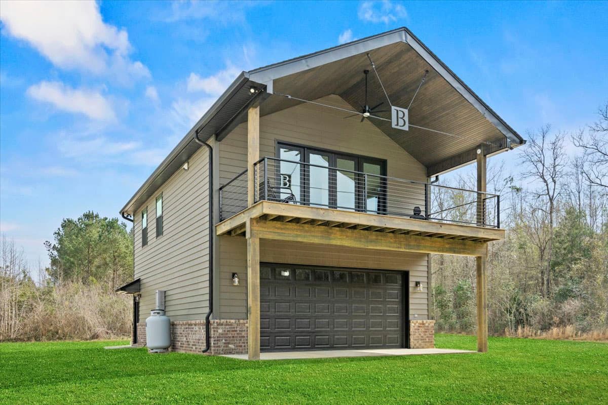 House plan exterior: Two-story modern design with a two-car garage, upper-level deck, and a standing seam gable roof.