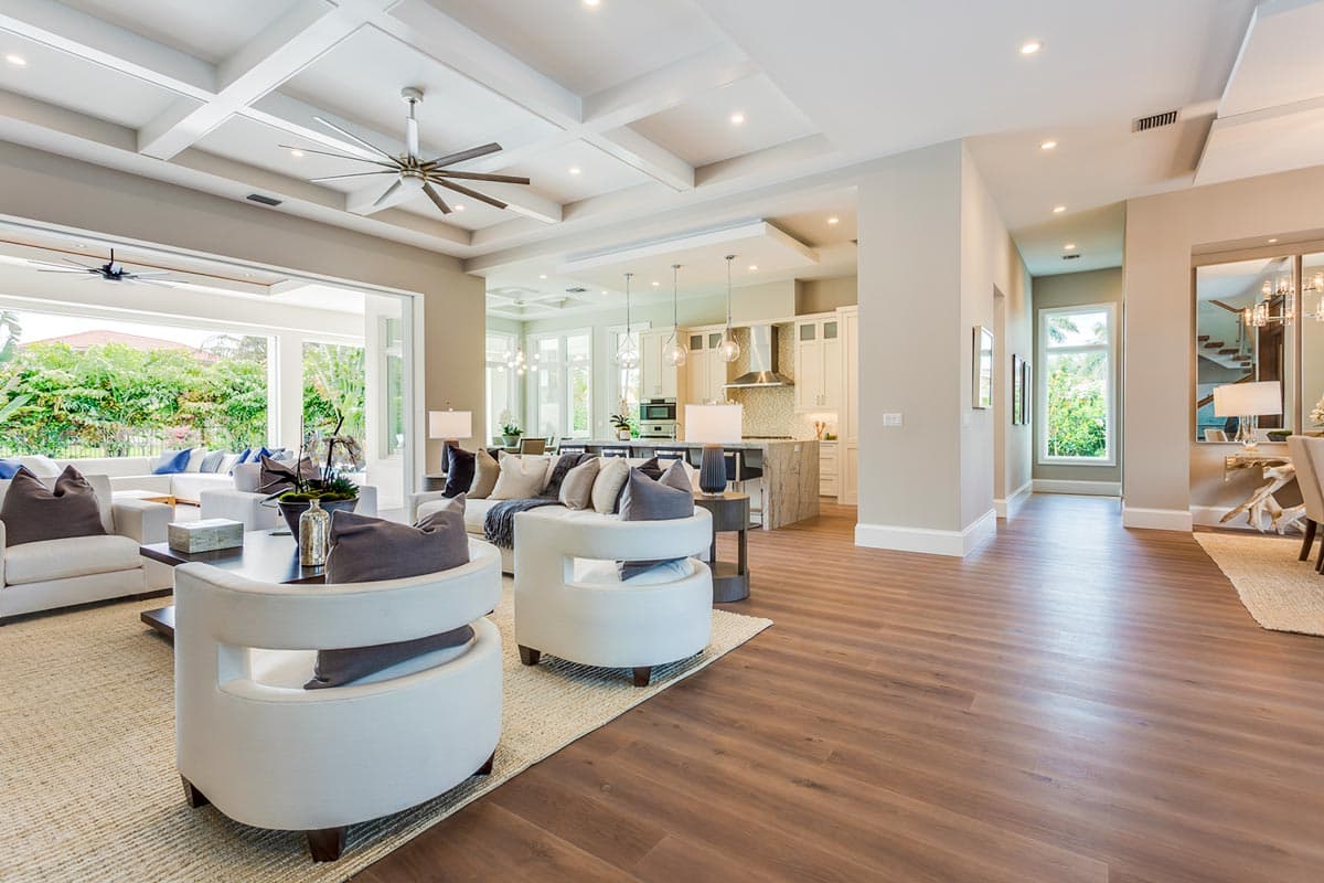 Open concept living area with coffered ceiling, large windows, and island kitchen. House plan interior.