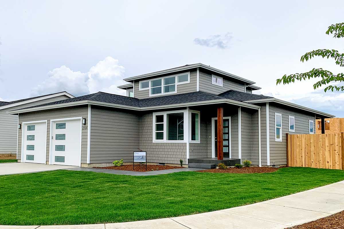 House plan exterior. Two-story Modern house with a flat roof, prominent upper windows, and a covered porch supported by wood columns.