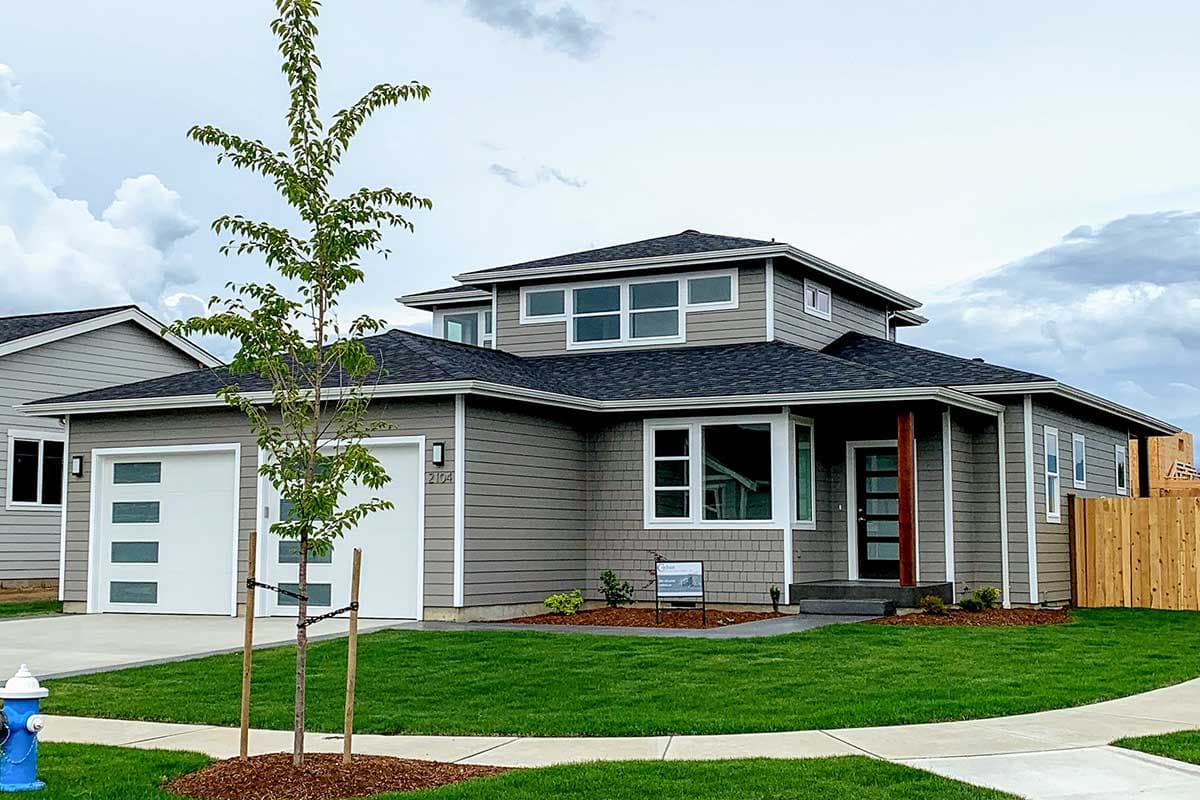 House plan exterior: Modern style, two-story, two-car garage with glass panels, covered entry with wood post, and multiple gables.