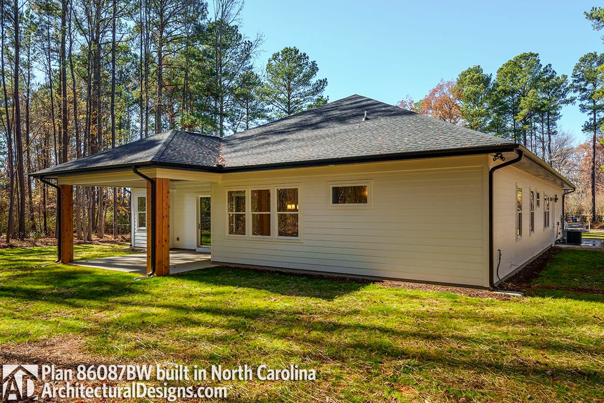 Ranch house plan exterior with covered patio, wood post supports, and multiple gabled rooflines.