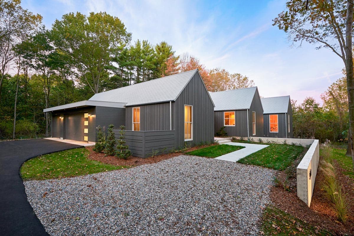 Modern house plan exterior with dark vertical siding, gabled roofs, and attached three-car garage.