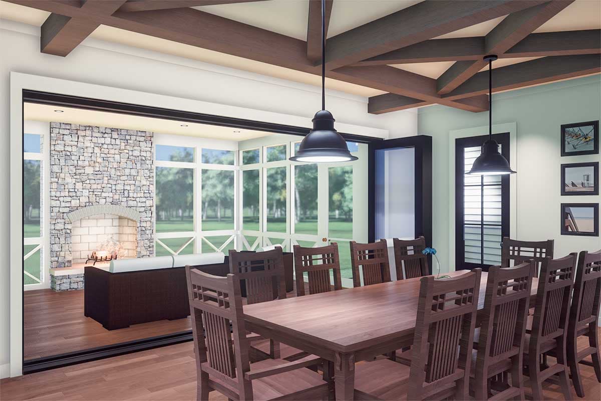 Dining room with large wood table and chairs, stone fireplace, and numerous windows.
