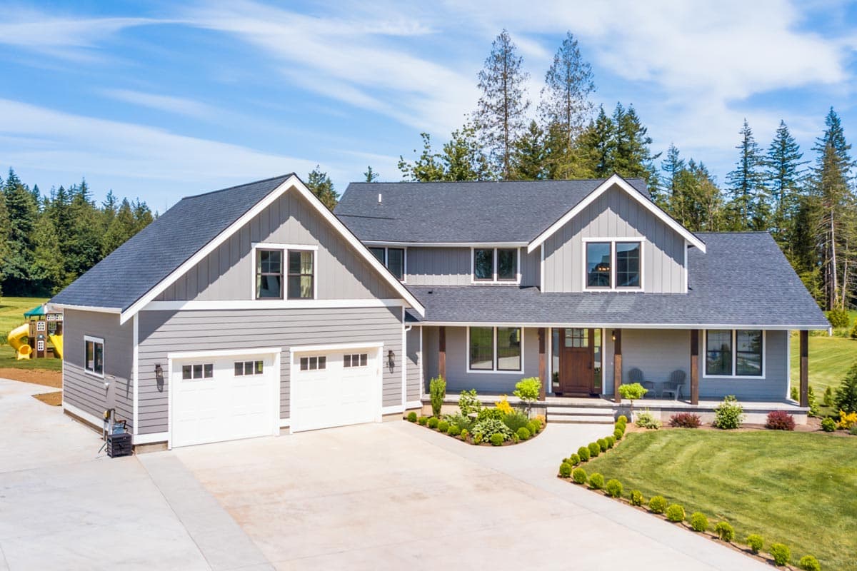 House plan exterior: Modern Farmhouse style, two stories, with a three-car garage, gables, dormers, and a covered front porch.
