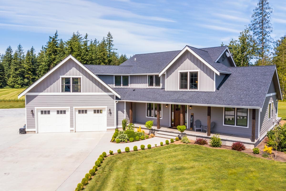 House plan exterior. Two-story Modern Farmhouse with a gabled roof, covered porch, and attached garage. Includes dormers and board-and-batten siding.