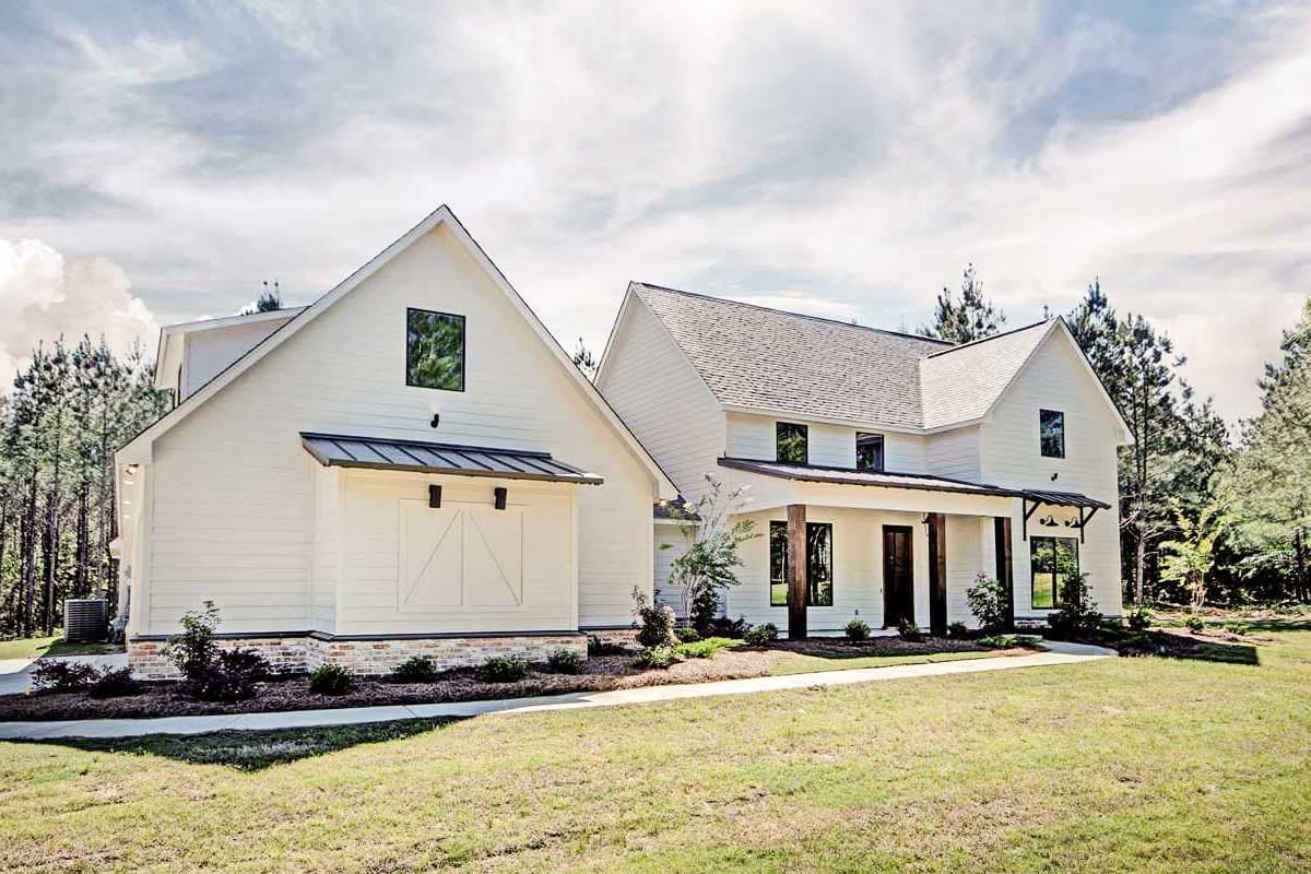 House plan exterior. Two-story Modern Farmhouse with gables, a covered porch with exposed beams, and a detached garage with barn doors.