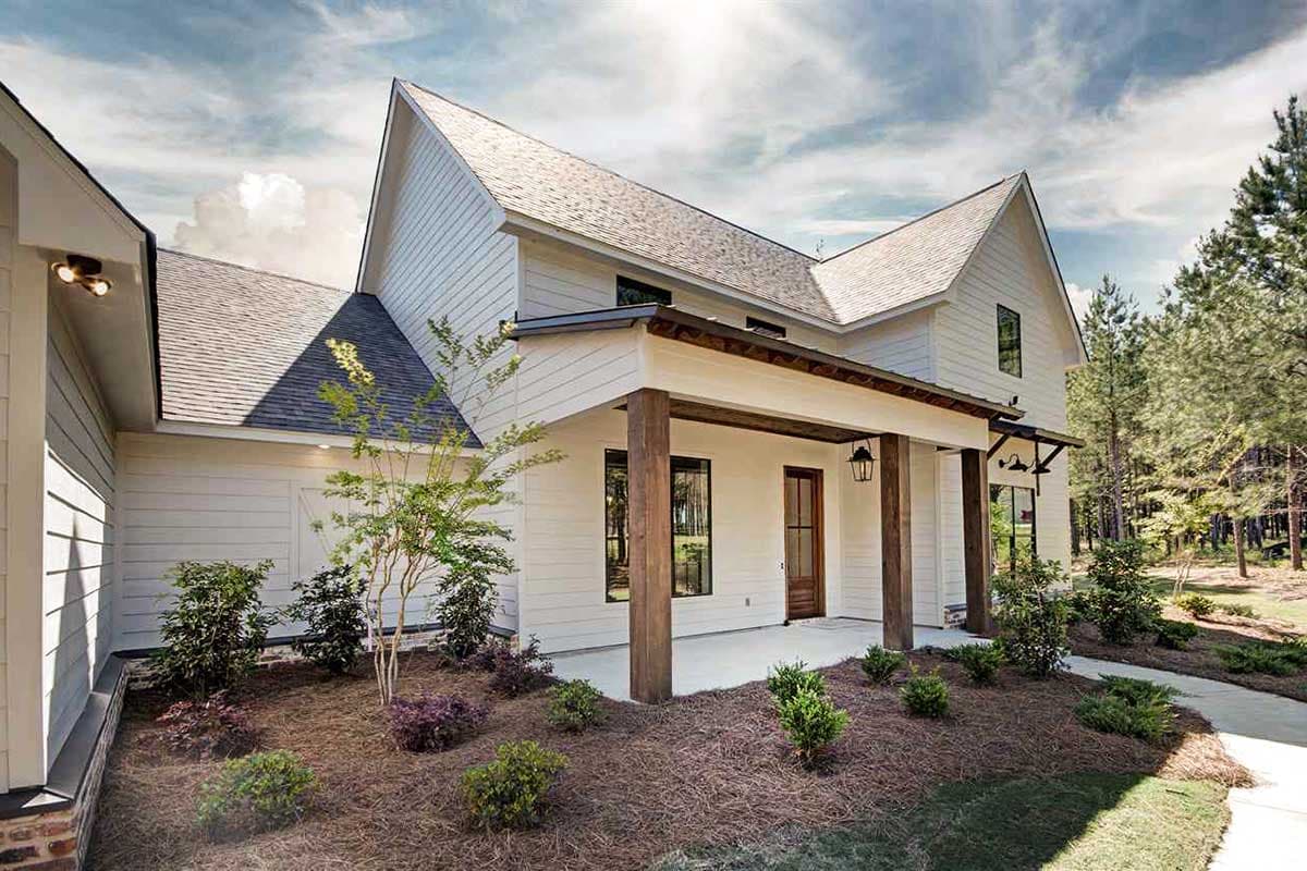House plan exterior: Modern Farmhouse style, two stories, wide front porch with timber posts, prominent gables, and board-and-batten siding.