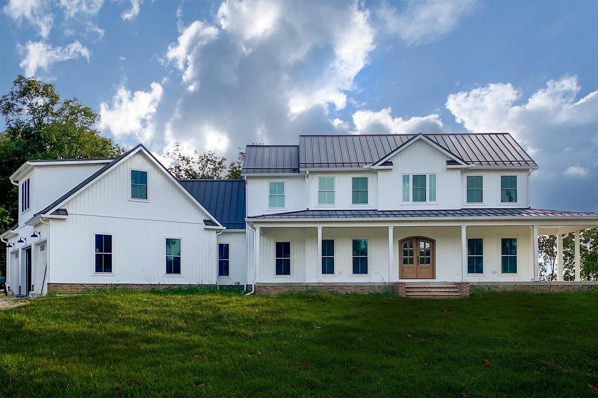Modern Farmhouse house plan exterior with metal roof, full-wrap porch, multiple gables, and attached garage.