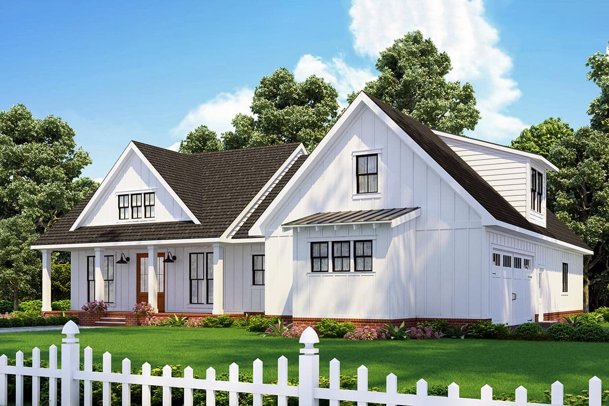 A modern white farmhouse with a dark roof and a front porch, framed by a white picket fence, a green lawn, and lush trees.