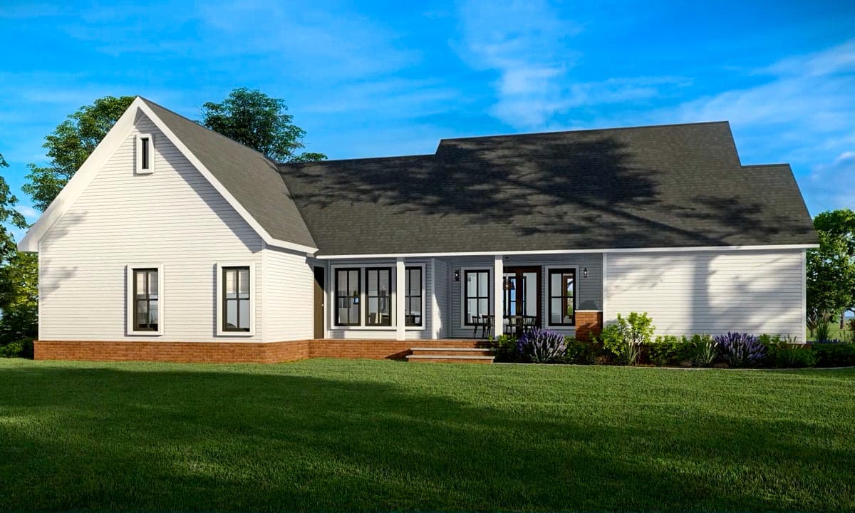 A modern, white-sided house with black-framed windows and a porch, set on a green lawn against a blue sky. Some bushes and trees in the background.