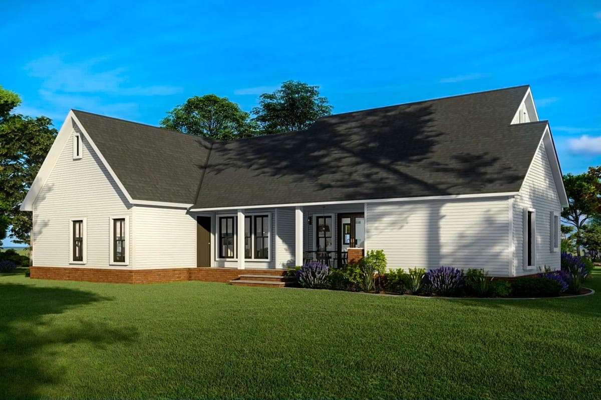 A white house with a dark roof and a covered porch. Lush green grass and a vibrant blue sky create a serene atmosphere.