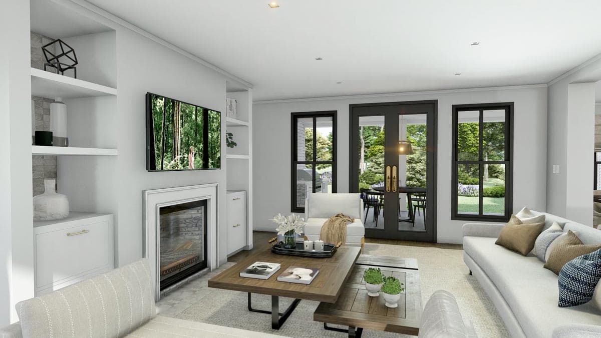 Modern living room with fireplace, built-in shelving, and a large window overlooking a lush green yard with seating. A coffee table is in the middle.