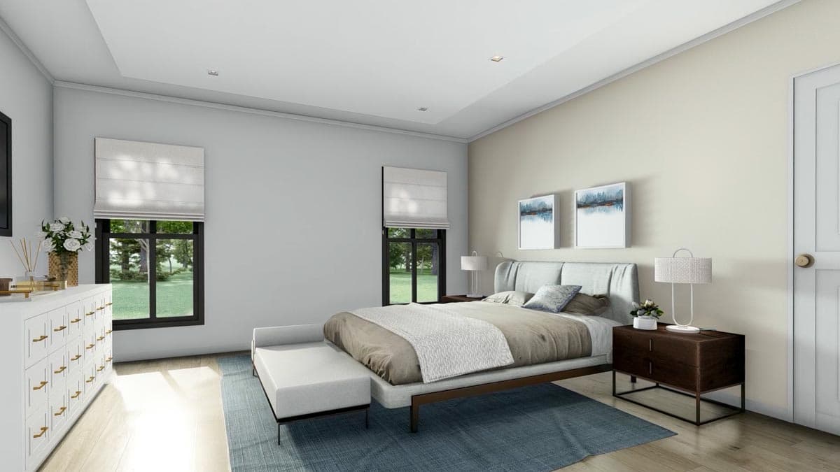 A modern bedroom with a bed, bench, and two side tables. Large windows with shades offer a view of the outdoors. Artwork hangs above the bed.