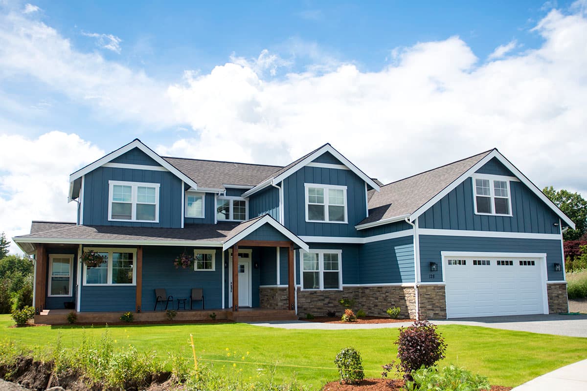 House plan exterior: Blue two-story home with gables, stone accents, front porch, and attached garage.