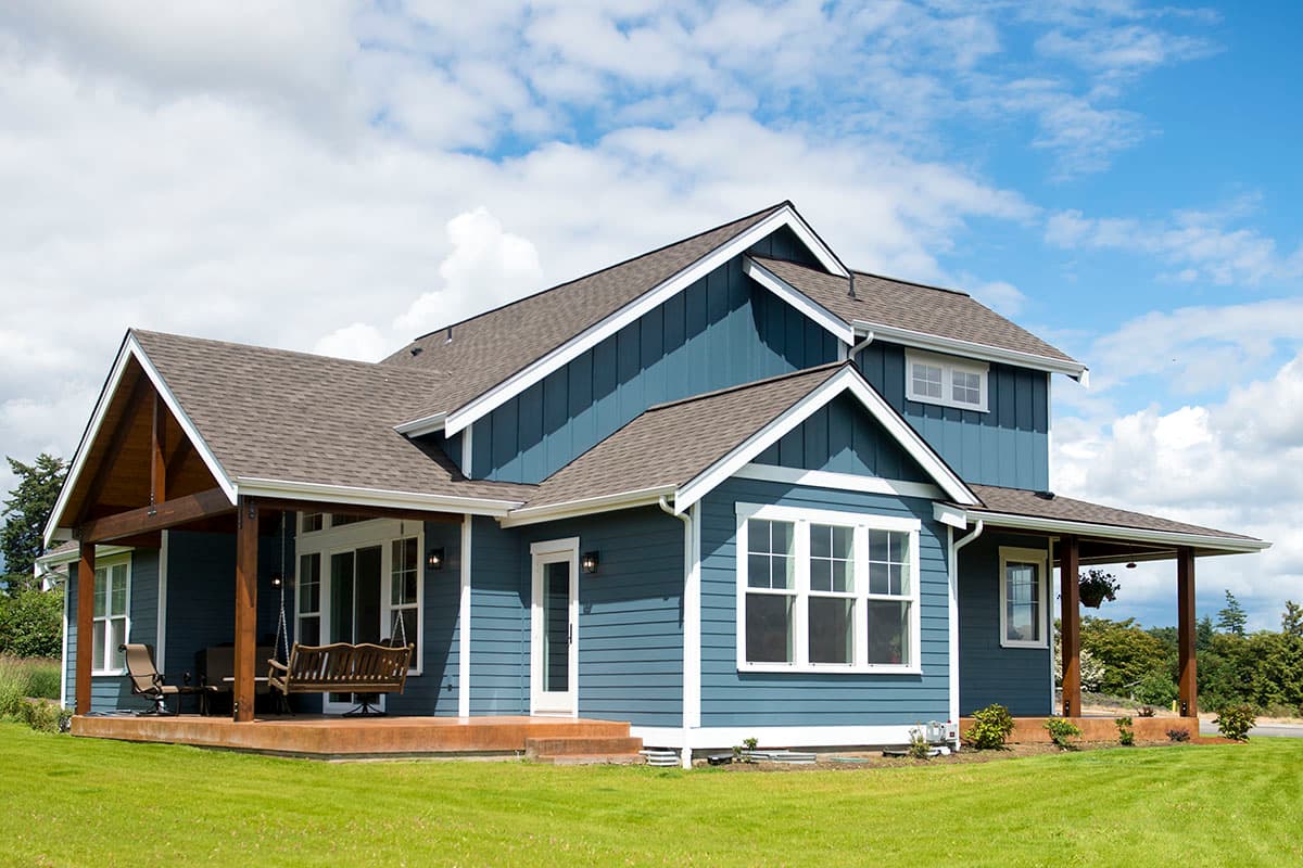 House plan exterior: Blue Modern Farmhouse with gabled roof, wide covered front porch with swing, and multiple dormers.