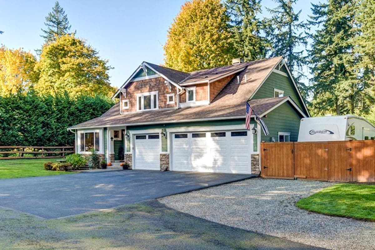 Two-story Craftsman house plan exterior with wood shake gables, a front-facing three-car garage, and a covered porch.