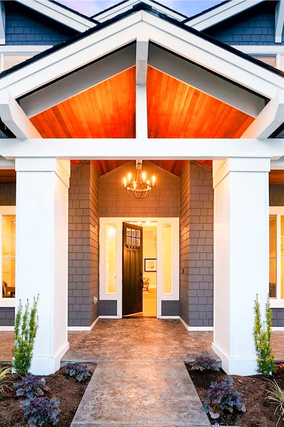 House plan exterior: Covered entry with timber-framed gables, shake siding, and double doors.