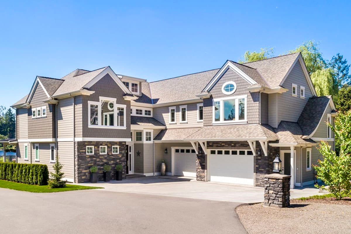 House plan exterior with multi-gabled roof, stone accents, and two-story structure. Features a garage and decorative gable end.