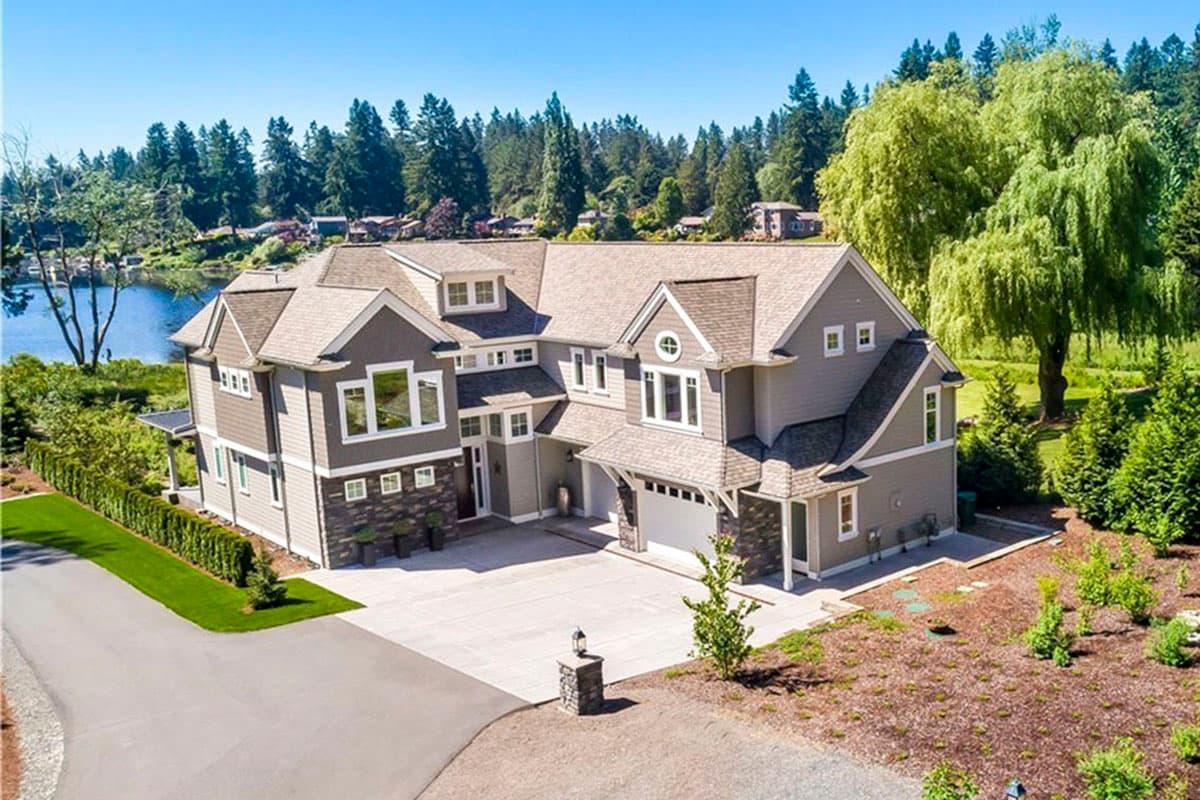 House plan exterior: Two-story home with multiple gables, dormers, and an attached garage. Features stone accents and a covered entry.