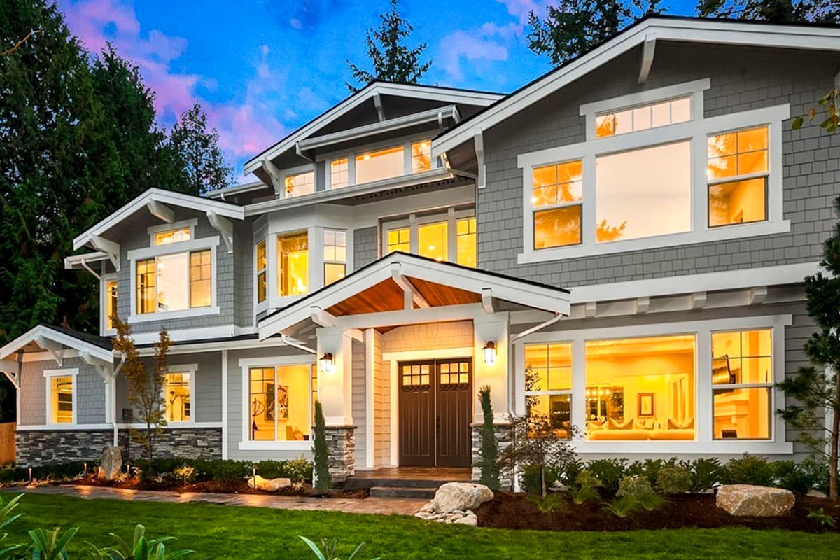 House plan exterior. Two-story Craftsman home with gabled rooflines, stone accents, and covered entry porch with timber detailing and columns.
