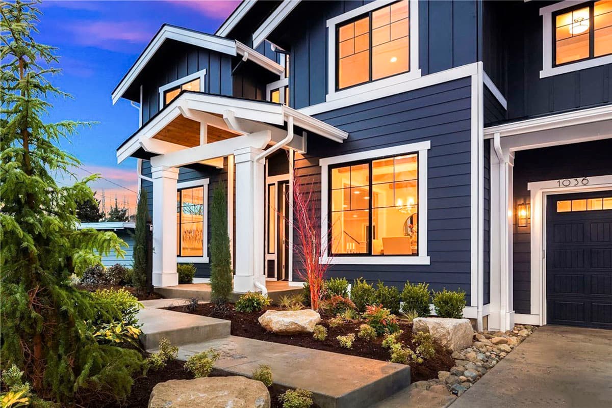 Modern house plan exterior with dark siding, white trim, covered entry, large windows, and attached two-car garage.