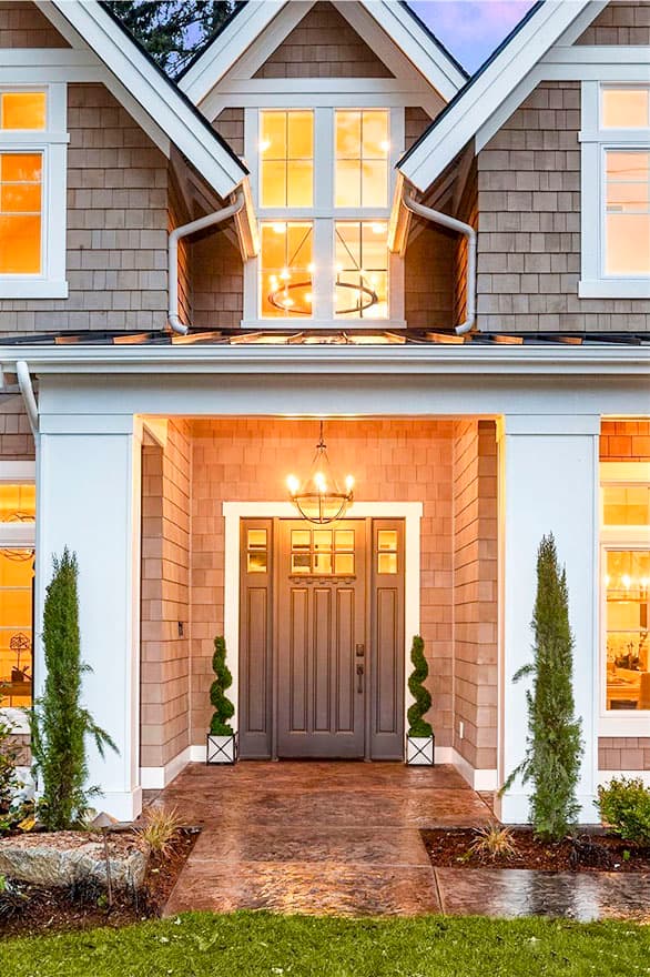 House plan exterior featuring shingle siding, covered entryway with glass-paneled door, and multi-story windows.