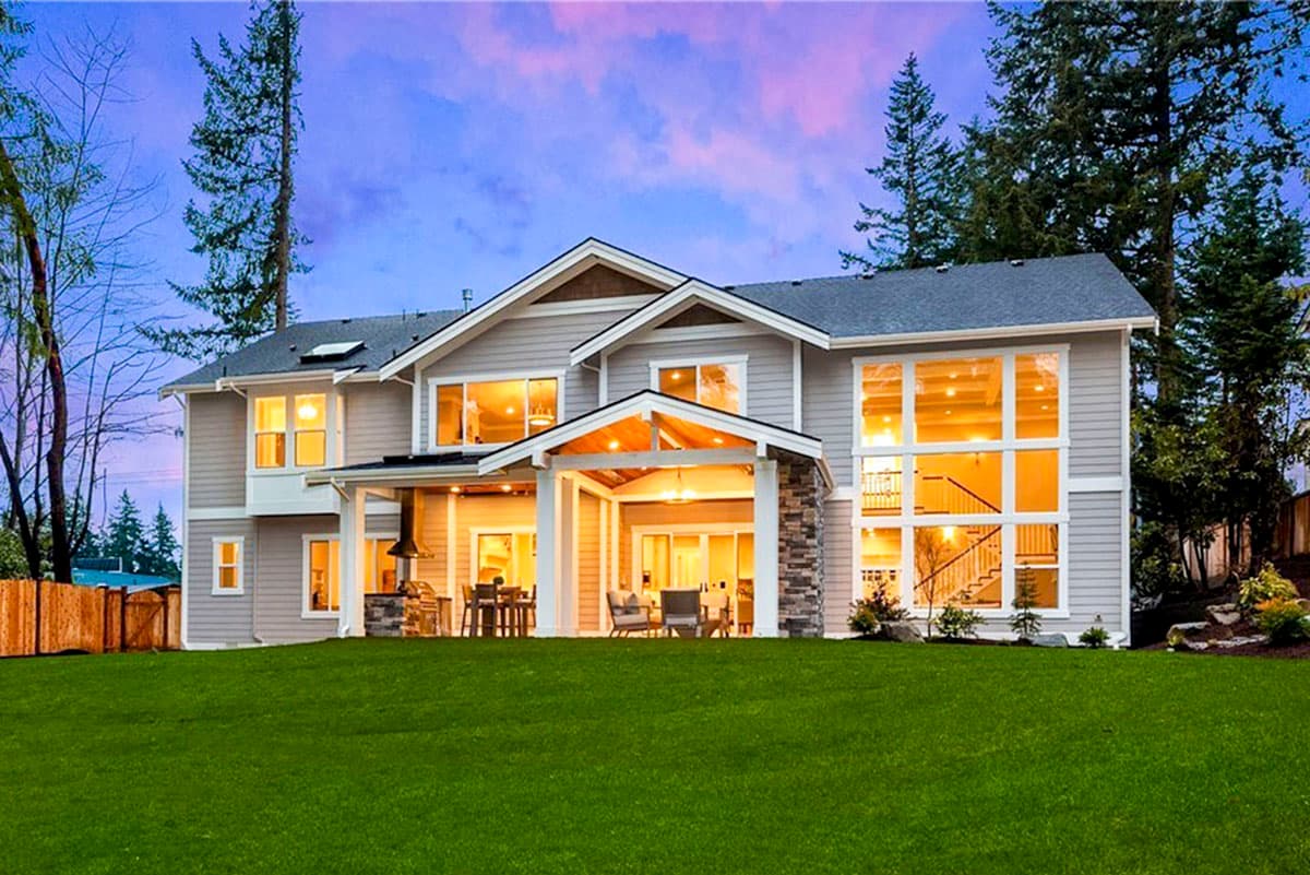 House plan exterior of a two-story home with a covered patio, stone accents, multiple gables, and large multi-pane windows.