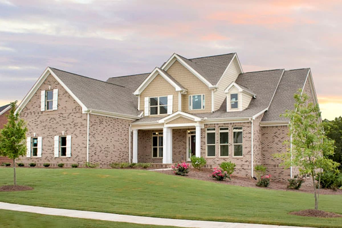 House plan exterior. Two-story home with a gabled roof, brick facade, and front porch. Includes dormers and symmetrical window placement.