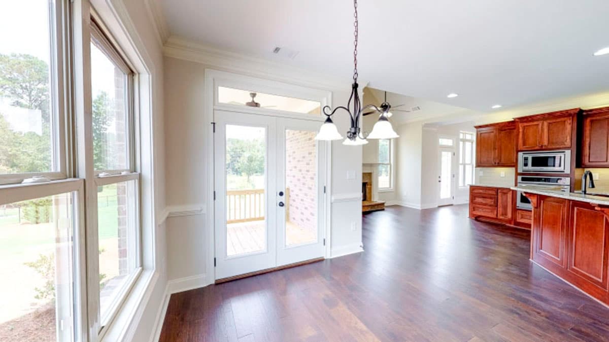 Open-concept dining area and kitchen with dark wood cabinetry, stainless steel appliances, large windows, and double doors to a deck.