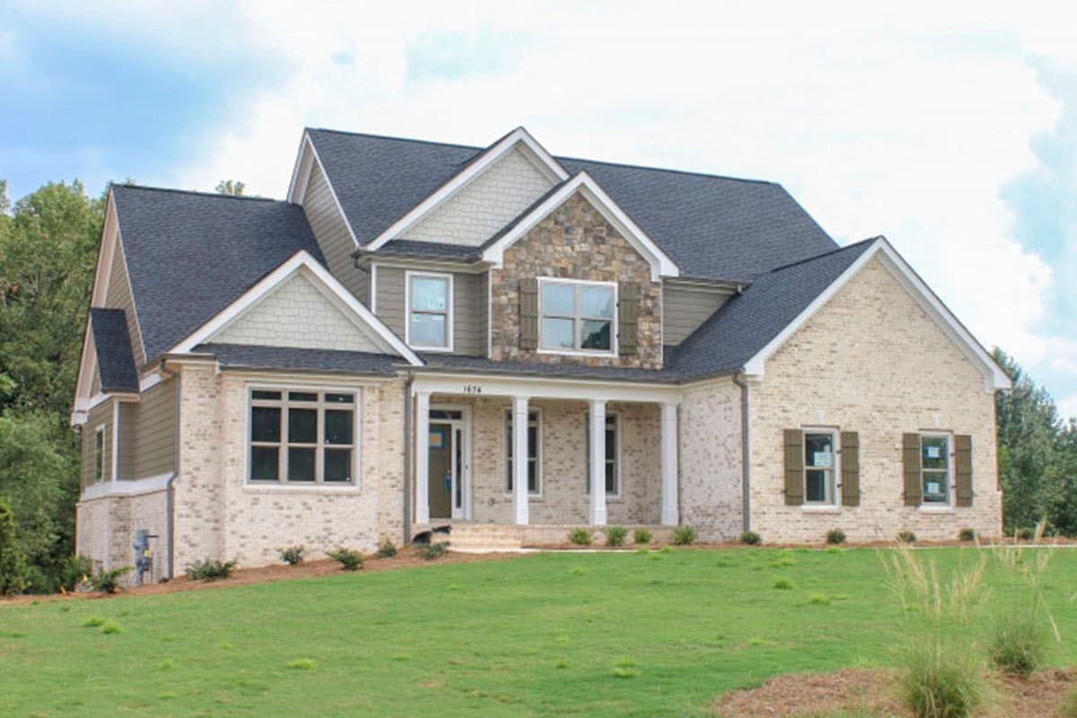 House plan exterior. Two-story home with Craftsman-style elements. Features include a front porch, multiple gables, and stone accents.