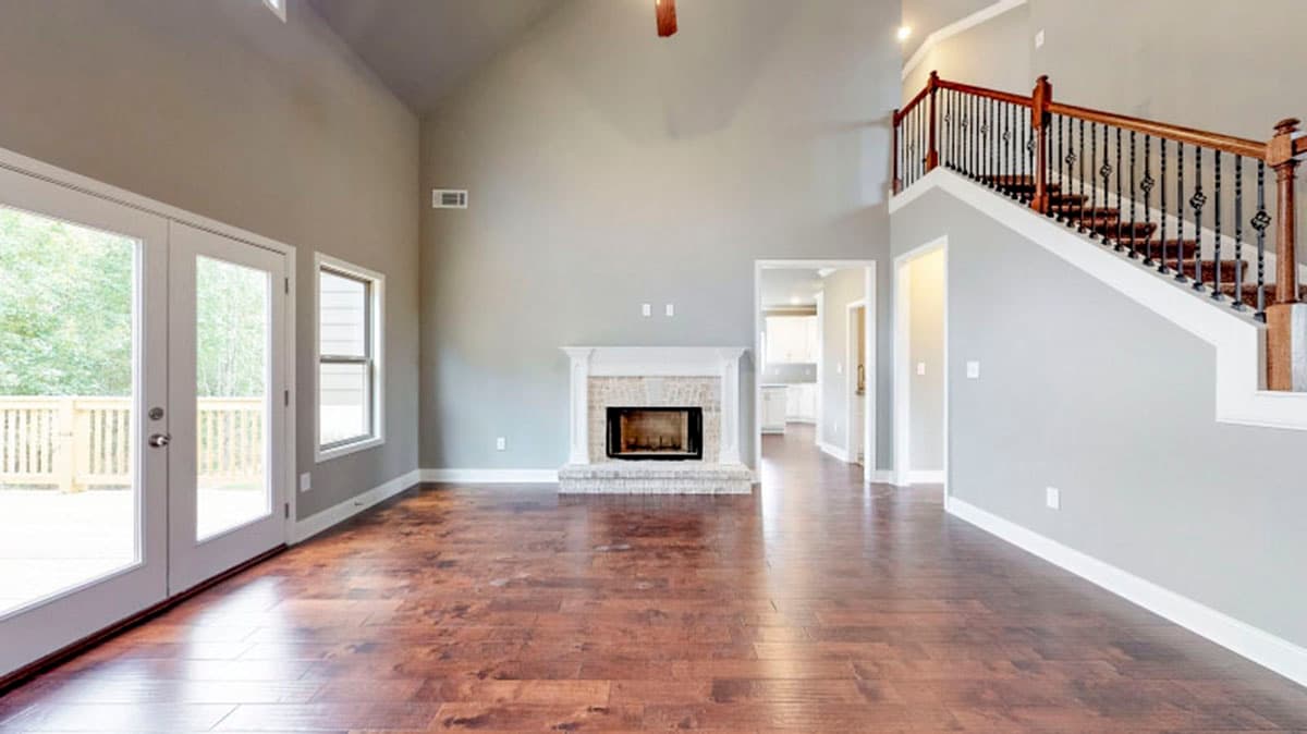 Interior view of great room with vaulted ceiling, fireplace, and stairs with decorative railing.
