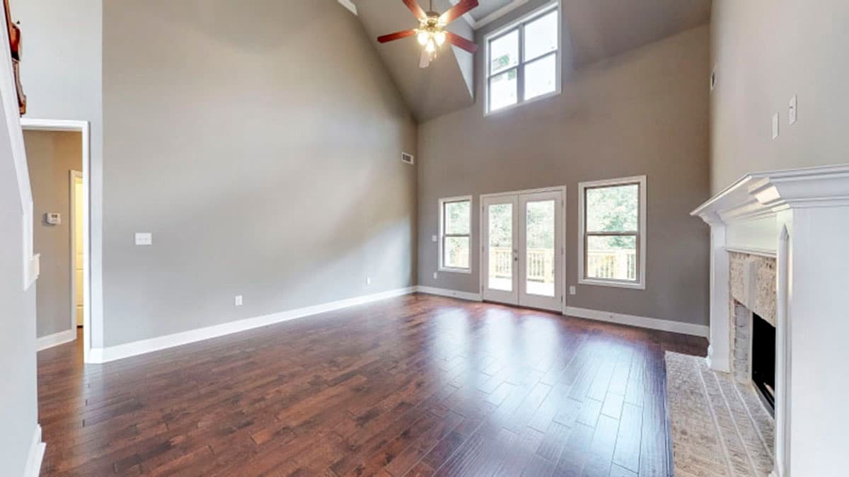 Great room with vaulted ceiling, fireplace, and double doors leading to a deck.