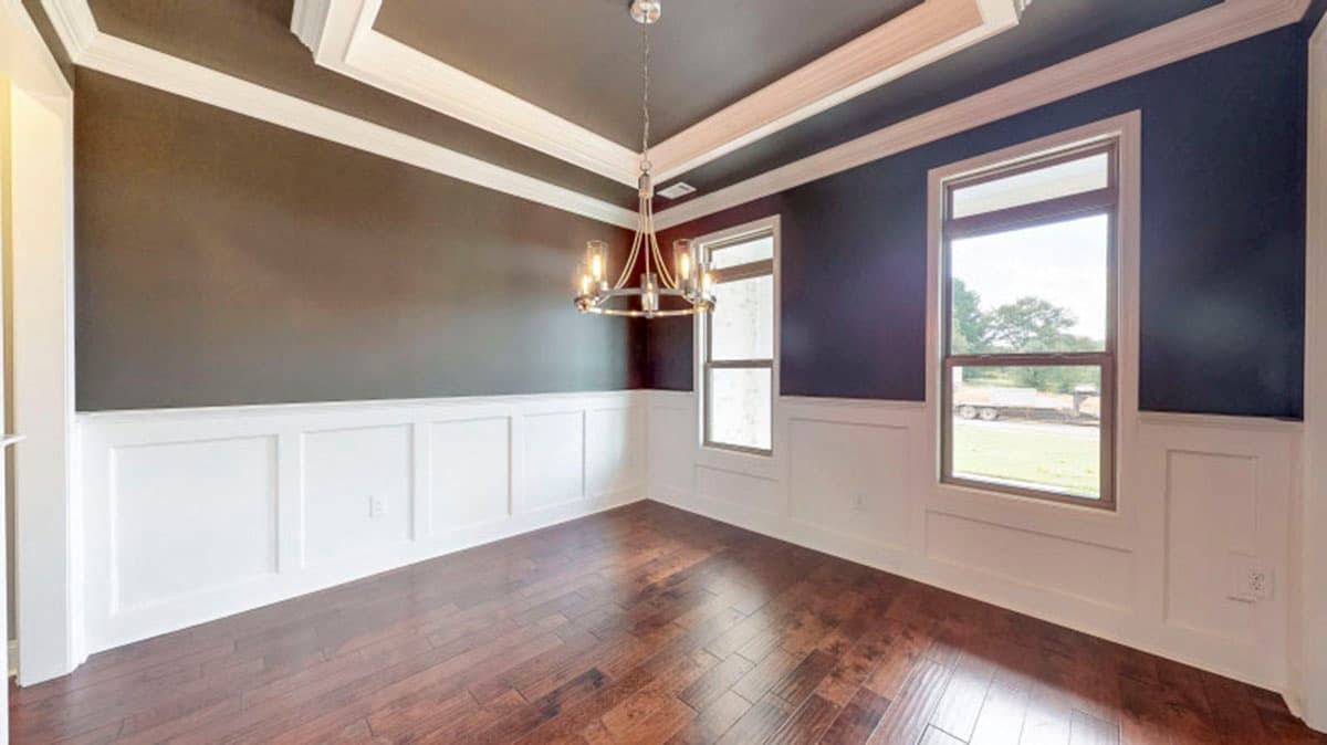 Dining room with coffered ceiling, wainscoting, hardwood floors, and a chandelier.
