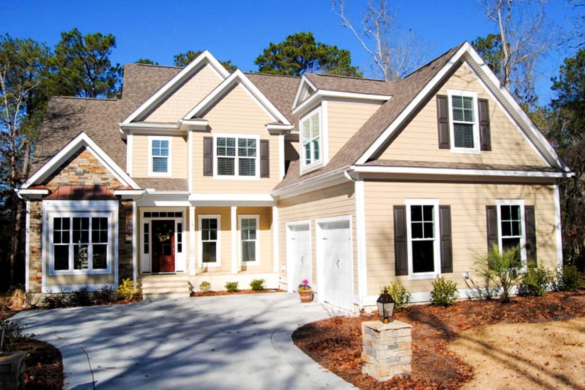 House plan exterior. Two-story home with multiple gables, a covered porch, and a side-entry garage. Features include stone accents and dormers.