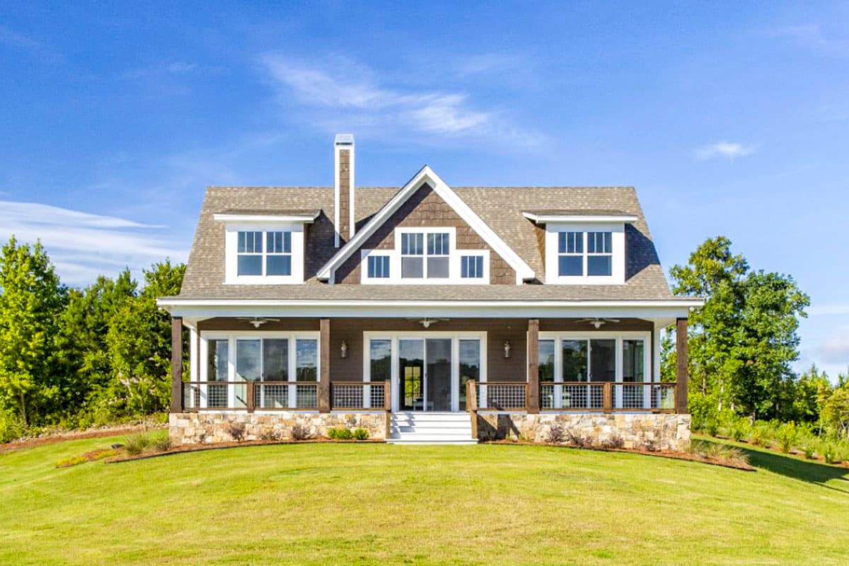 House plan exterior. Two-story home with Craftsman style. Features include a front porch with railing, multiple gables, and a prominent chimney.