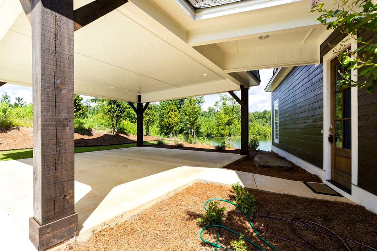 House plan exterior with covered patio, dark wood columns, and horizontal siding.