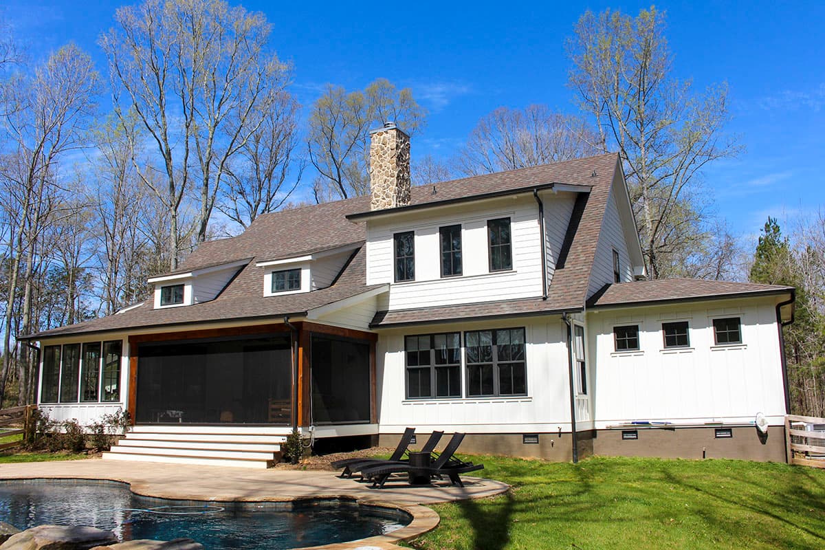 House plan exterior: Two-story Modern Farmhouse with stone chimney, screened porch, gabled dormers, and multi-pane windows.