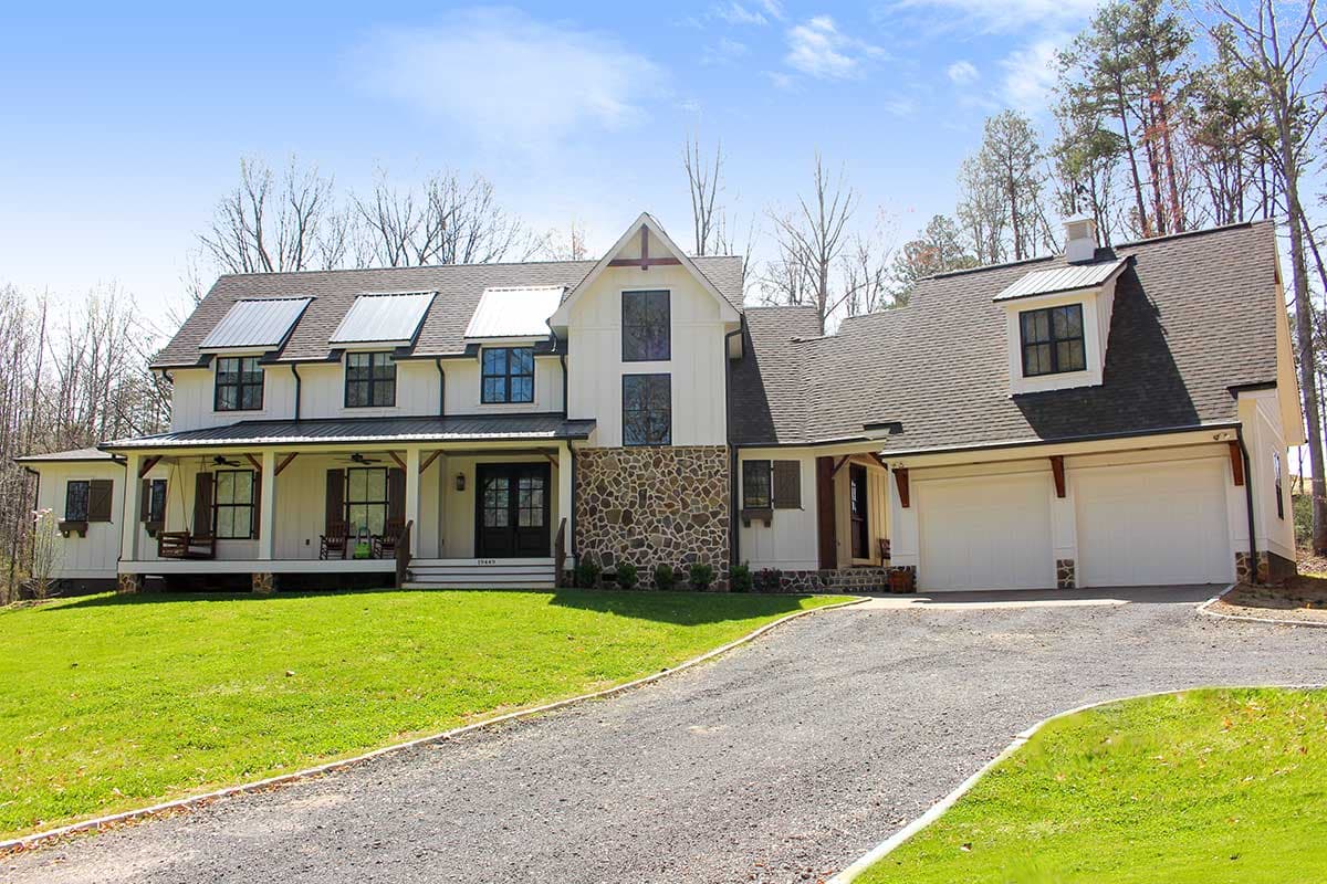 House plan exterior. Two-story Modern Farmhouse with a gabled roof, stone facade accent, front porch, and attached garage with dormer window.